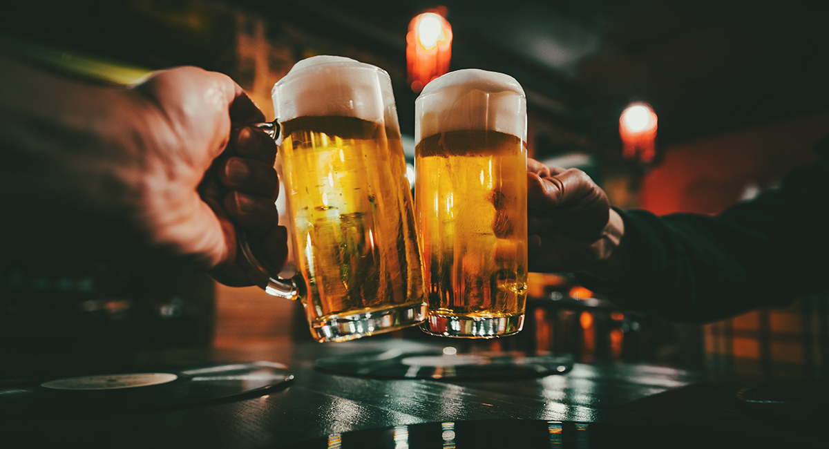 Closeup view of a two glass of beer in hand. Beer glasses clinki