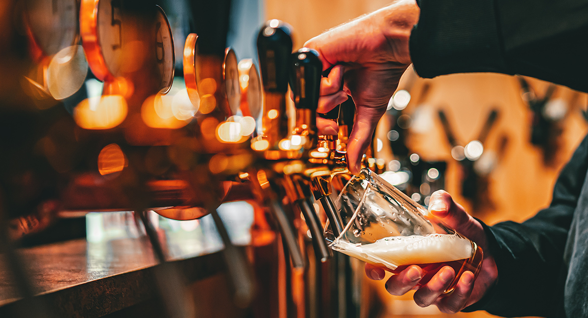 bartender hand at beer tap pouring a draught beer in glass servi